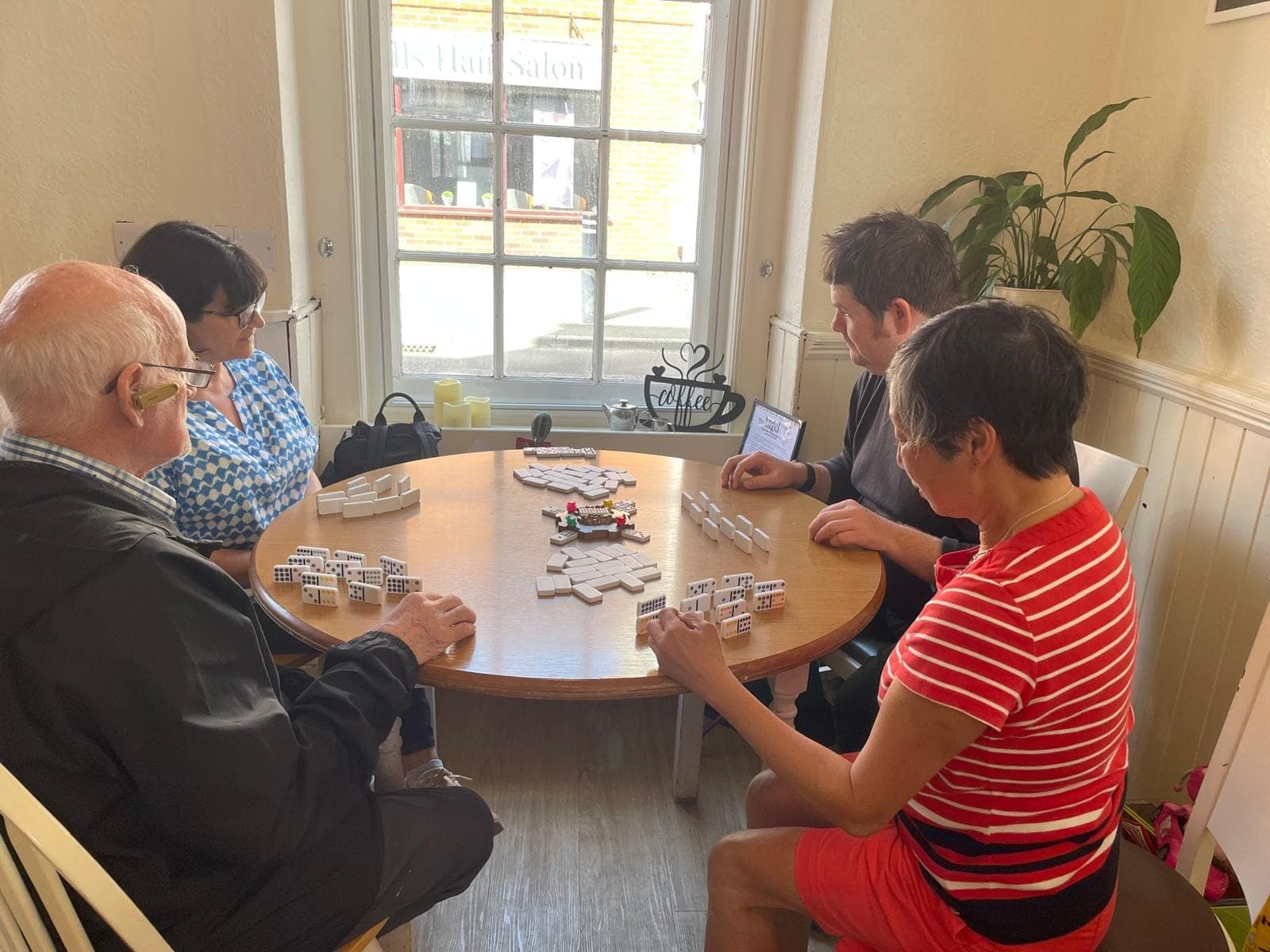 People playing dominoes together around a table in the café