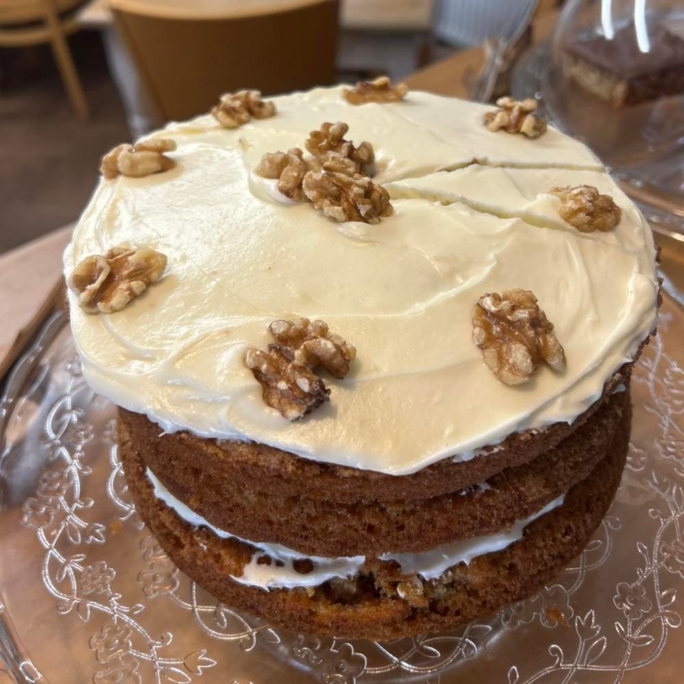A coffee and walnut cake on a glass cake stand