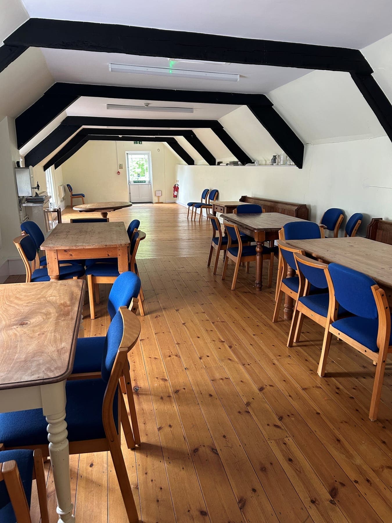The upstairs meeting room at The Angel, with a beamed ceiling, wooden floor and tables set out for a meeting