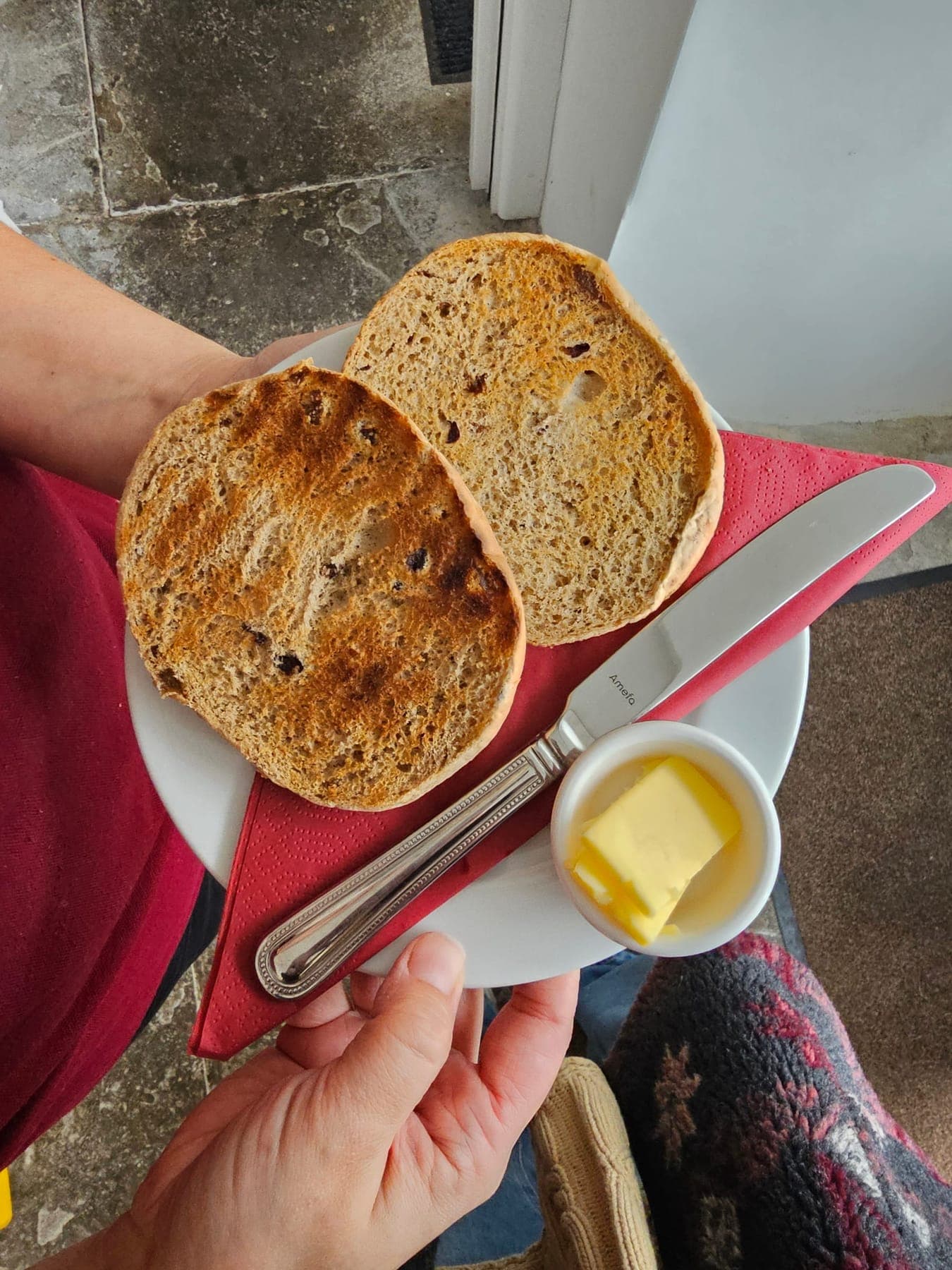A toasted fruited tea cake, halved and served with a pot of butter
